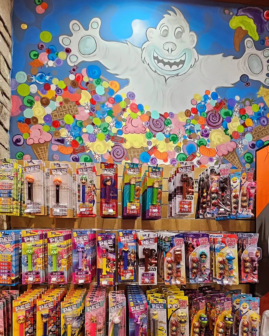 The yeti mural with raining candy above the Pez wall inside The Snack Shack