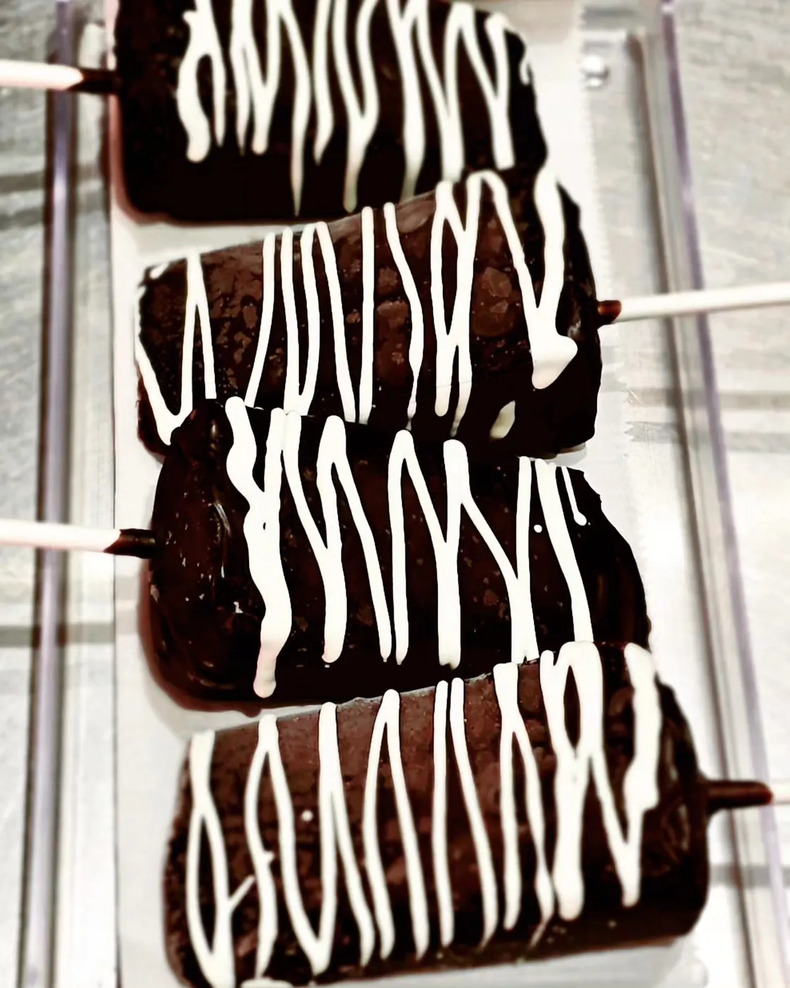 Chocolate-dipped treats on sticks with white chocolate drizzle